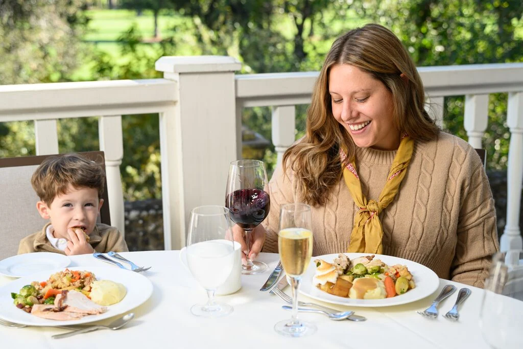 A woman and a young boy share a holiday meal with wine at a sunny deck table at Silverado Resort